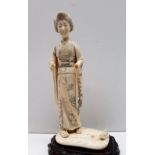 A 19th century ivory figure of a geisha, in a kimono on a rectangular base,