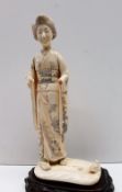 A 19th century ivory figure of a geisha, in a kimono on a rectangular base,