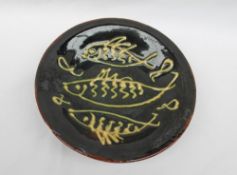 An Islwyn Watkins studio pottery dish, with slip decoration of fish to a brown ground,
