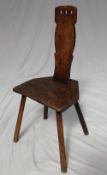 An 18th century elm spinning stool, the slat back with three ring finger holes to the top,