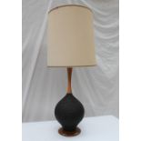 A 20th century turned walnut and textured ribbed black pottery table lamp, on a walnut base,