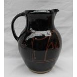A large studio pottery jug, with a dark brown glaze with light brown decoration,