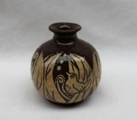 A studio pottery vase slip decorated with a bird amongst leaves in brown and cream,