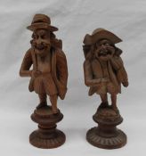 A pair of Black Forest carved figures with baskets upon their back, on circular carved bases, 13.