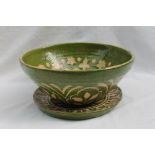 A studio pottery tapered bowl decorated with flower heads and leaves to a green ground,