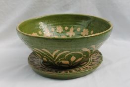 A studio pottery tapered bowl decorated with flower heads and leaves to a green ground,