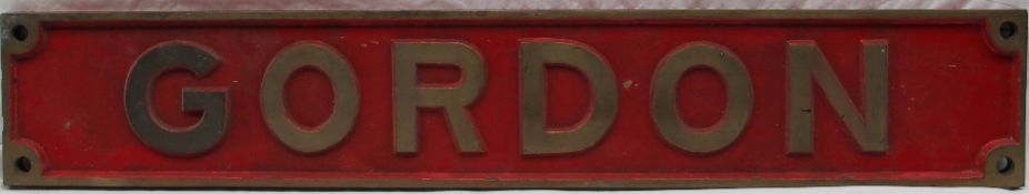A rectangular bronze railway name plate "Gordon" to a red ground,