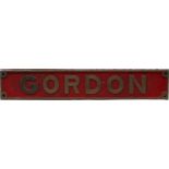 A rectangular bronze railway name plate "Gordon" to a red ground,