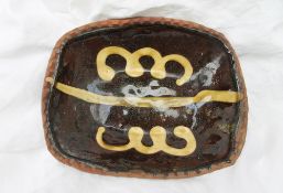 A slipware dish of rectangular form with mustard yellow decoration to a brown ground, 19.5 x 15.