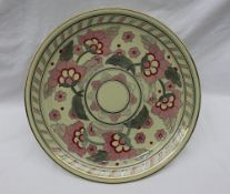A Crown Ducal pottery charger decorated with pink and red flowers to a lime green ground,