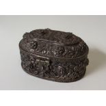 A white metal box and cover of oval form profusely decorated with flower heads and leaves,