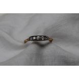 A five stone diamond ring set with five round old cut diamonds to a white metal setting and