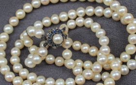 A two strand pearl necklace set with sixty regular shaped to one strand and forty eight to the