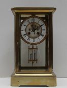 A Brass four glass mantle clock, with an enamel dial with Roman numerals and an insight movement,