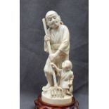 A 19th century ivory figure group of a man and child holding a five point fishing trident,