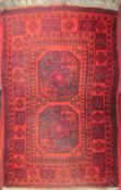 A red ground rug with two geometric panels to the centre and multiple guard stripes,