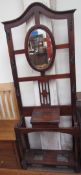 A 20th century hall stand, the arched top above an oval mirror and hooks,