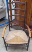 A late 19th century ladder back elbow chair with a rush seat on tapering legs