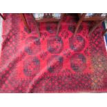 A large red ground rug with eighteen geometric guls and broad guard stripes,