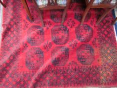 A large red ground rug with eighteen geometric guls and broad guard stripes,