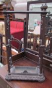 A cast iron stick stand with three openings and a drip tray