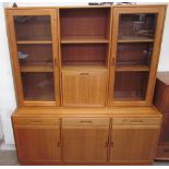 A teak wall unit, the top section with a pair of glazed doors and fall front,