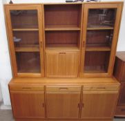 A teak wall unit, the top section with a pair of glazed doors and fall front,