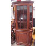 A reproduction oak standing corner cupboard with a moulded cornice above a glazed door,