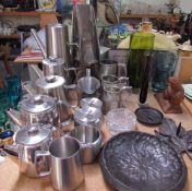 A stainless steel part tea set together with other stainless steel items,