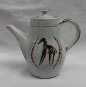A studio pottery coffee pot, with a white glaze and decorated with stylised horses in browns,