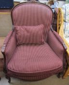 A Victorian style library chair with a carved back and striped upholstery