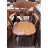 An oak captain's chair with a spindle back and arms open cabriole front legs