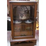 An oak cased smokers cabinet with a rectangular moulded top above a glazed doors fitted with