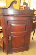 An 18th century oak hanging corner cupboard with a moulded cornice above a two panelled door