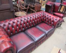 A red leather chesterfield settee together with a matching armchair,