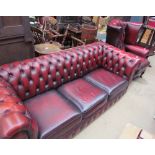 A red leather chesterfield settee together with a matching armchair,