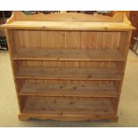 A modern pine bookcase with a shaped top and shaped plinth base