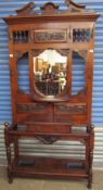 An Art Nouveau inspired oak hall stand with turned spindles, coat hooks, a shield shaped mirror,