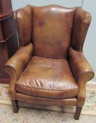 A pair of George III style brown leather wing back armchairs on square legs