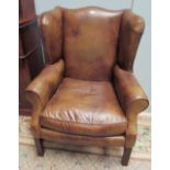 A pair of George III style brown leather wing back armchairs on square legs