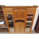 An Edwardian satin walnut triple wardrobe, with a moulded cornice above a pair of mirrored doors,