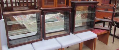 Three glazed hanging display cabinets together with oak hanging shelves