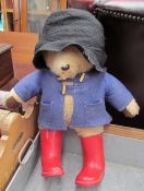 A Paddington bear teddy in black felt hat and red wellies