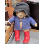 A Paddington bear teddy in black felt hat and red wellies