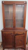 A 20th century oak bookcase with a moulded cornice above a pair of glazed doors,