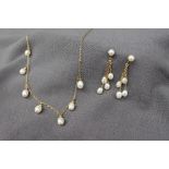 A pearl and yellow metal necklace set with seven oval pearls on a yellow metal chain with matching