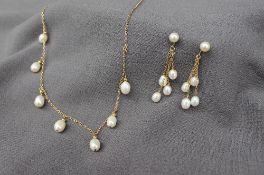 A pearl and yellow metal necklace set with seven oval pearls on a yellow metal chain with matching