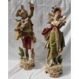 A pair of Royal Dux figures of musicians, in greens and reds on a naturalistic base,