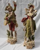 A pair of Royal Dux figures of musicians, in greens and reds on a naturalistic base,