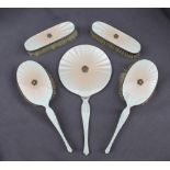A George V silver and cream enamel part dressing table set, comprising a hand mirror,